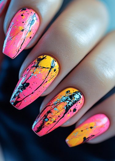 Vibrant pink and orange ombre nail art with edgy black splatters and blue glitter accents.