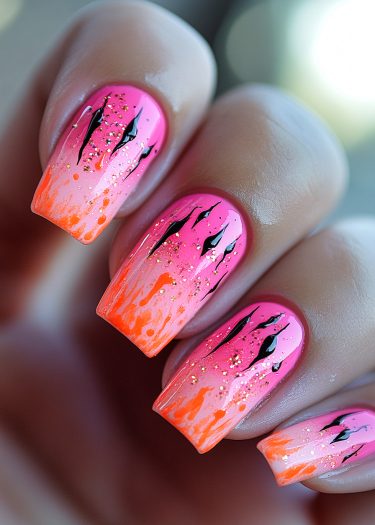 Vibrant gradient nails with pink-orange hues and bold black flame designs featuring glamorous glitter.