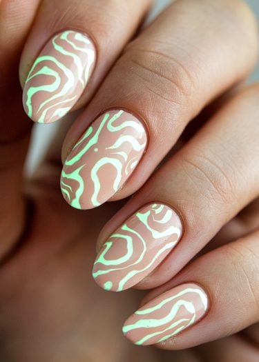 Elegant almond-shaped nails featuring vibrant green abstract designs on a neutral pink base.