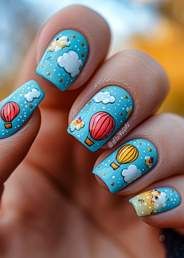 Colorful hot air balloon nail art on a vibrant blue background with whimsical clouds.