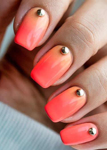 Vibrant ombre nail art with metallic studs for a stylish and sophisticated look.