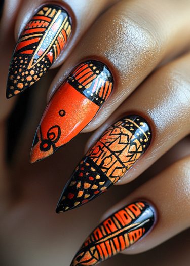 Vivid orange stiletto nails with intricate black geometric patterns and tribal designs for stunning nail art.