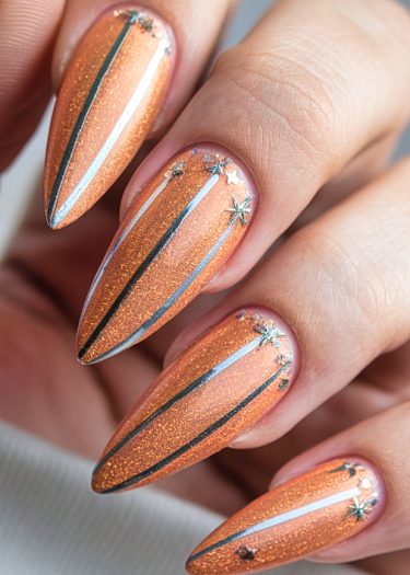 Elegant almond-shaped nails in vibrant orange with metallic stripes and star accents.