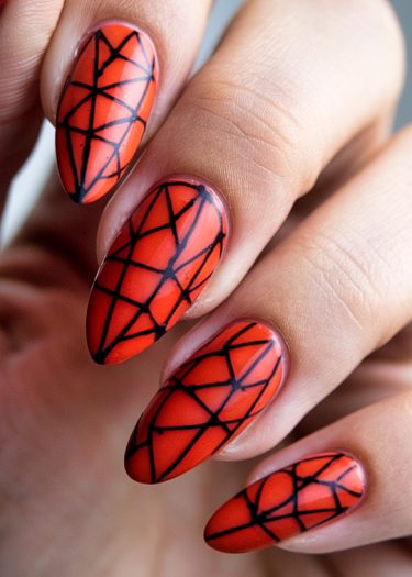 Stunning geometric red-orange nail art with intricate black designs on almond-shaped nails.