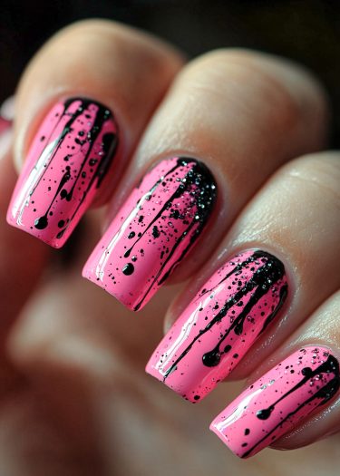 Bold pink nail art with black splatter design and glitter accents for a stylish look.