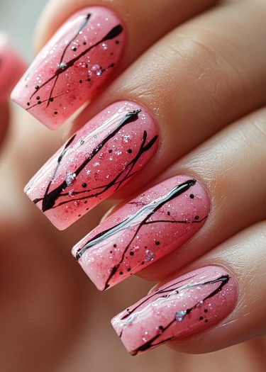 Elegant pink ombre nail art with intricate black designs and sparkling accents for stylish expression.