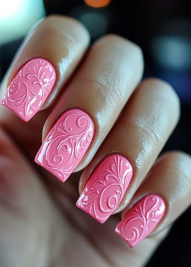 Elegant vibrant pink nails with intricate floral design and glossy finish in a close-up view.