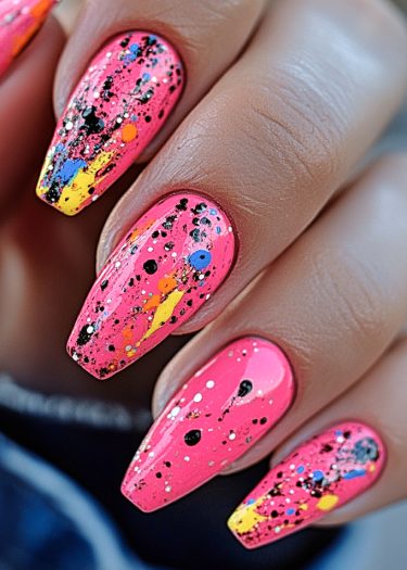 Elegant pink nail art with vibrant splatters in multiple colors showcasing creative design.