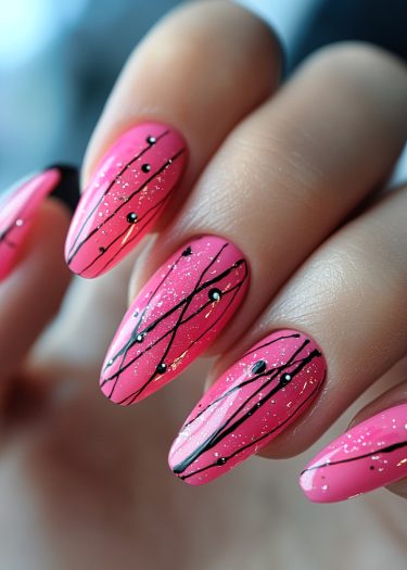 Vibrant pink stiletto nails with elegant black designs and sparkling rhinestones for a chic look.