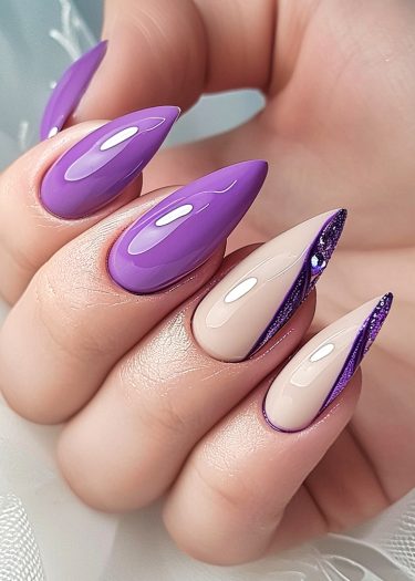 Vibrant purple stiletto nail art with glitter accents and gemstone details for elegant manicure.