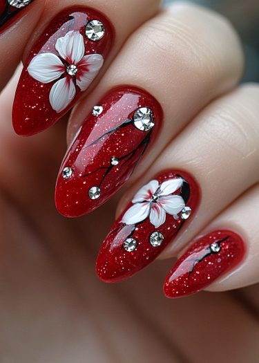 Exquisite red glitter nail art featuring elegant floral designs and sparkling rhinestones.