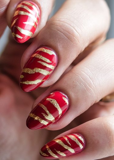 Elegant red nail art with gold metallic design, showcasing sophistication and creativity.