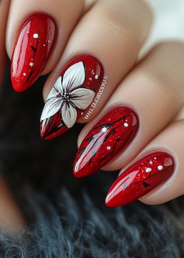 Stunning stiletto red nails with glitter, floral art, and modern black accents.