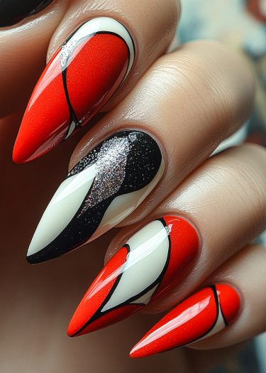 Bold stiletto nails featuring vibrant red, black, and silver abstract designs for modern nail art.