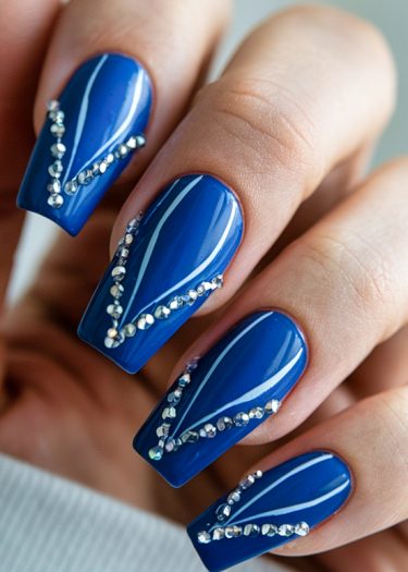 Elegant vivid blue nail art with rhinestones and intricate designs for a stylish look.