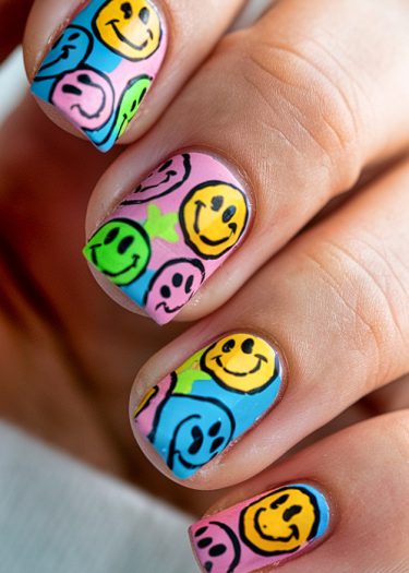 Bright nail art featuring colorful smiley faces creates a fun and cheerful design.