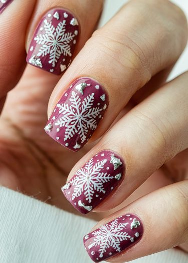 Elegant burgundy winter nail art with snowflakes and silver accents for festive celebrations.