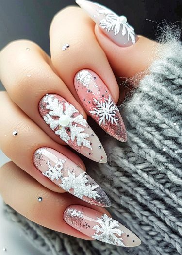 Elegant winter snowflake manicure with iridescent rhinestones and pink base on almond-shaped nails.