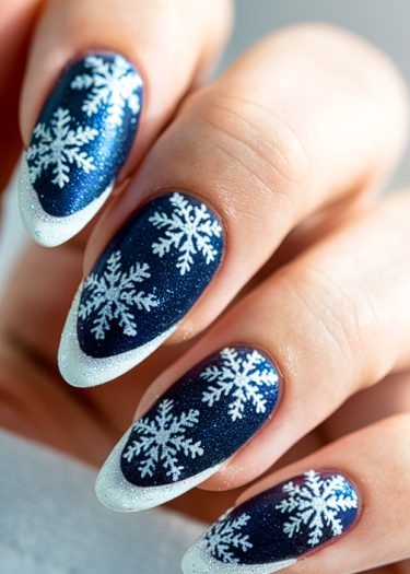 Elegant winter snowflake nail art in deep midnight blue with sparkling glitter tips.