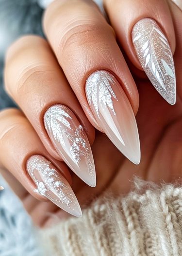 Elegant stiletto nails featuring winter leaf design in soft pink and shimmering glitter.