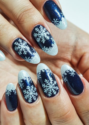 Elegant winter snowflake nail design with deep navy and shimmering white gradients.