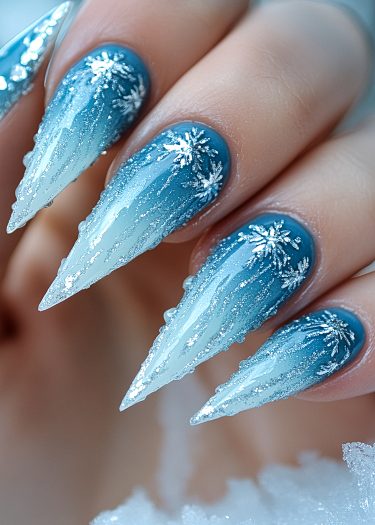 Elegant winter snowflake nails with icicle design and shimmering blue gradient.