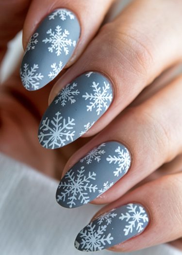 Elegant winter snowflake nail design on matte gray almond-shaped nails.