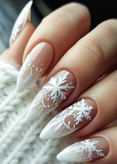 Elegant winter-themed nail art with intricate snowflake designs on long nude nails.