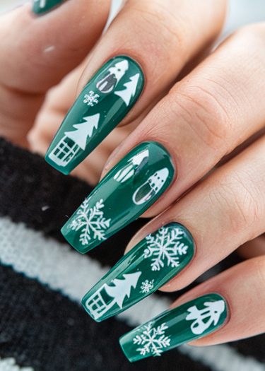 Elegant winter-themed nail art with snowflakes and snowy scenes on deep green nails.