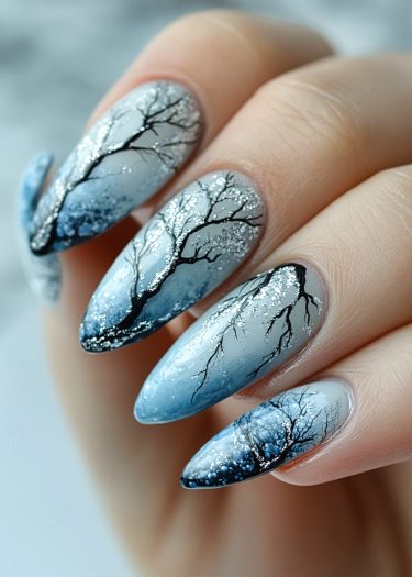 Beautiful winter tree nail art with icy blue gradient and shimmering glitter accents.