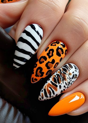 Vibrant zebra and leopard nail art with glossy orange accents on almond-shaped nails.