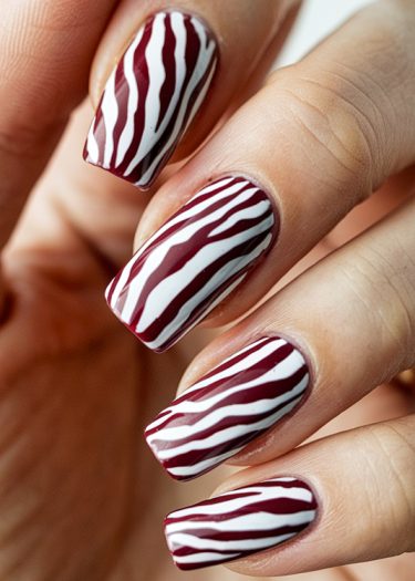 Stylish zebra-striped red and white nail design showcased on a manicured hand.